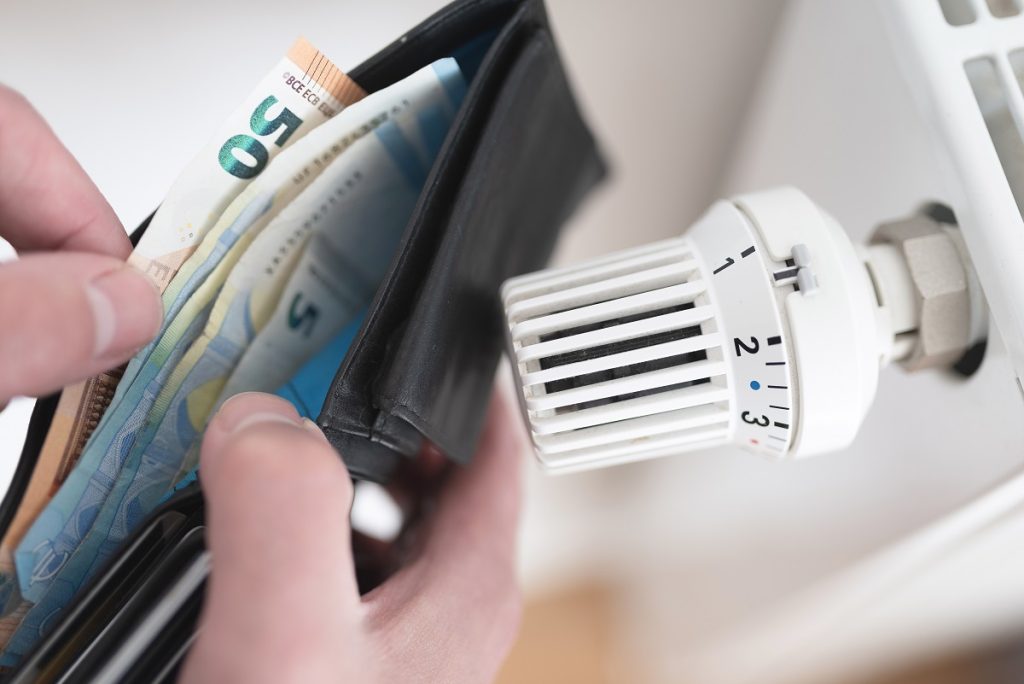 detailopname van handen met portemonnee bij radiatorknop