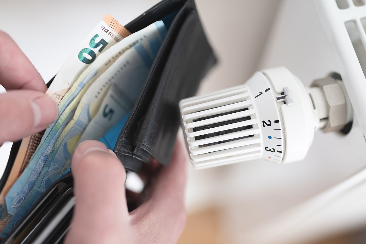 detailopname van handen met portemonnee bij radiatorknop