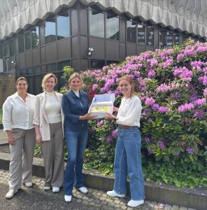 Collega's met een slagroomtaart om 10 jaar buurtgezinnen te vieren