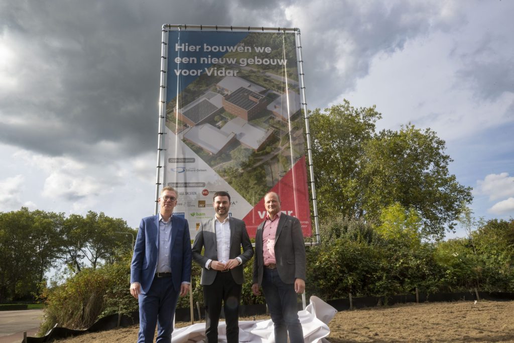 bouwbord met de tekst 'hier bouwen we een nieuw gebouw voor Vidar'.